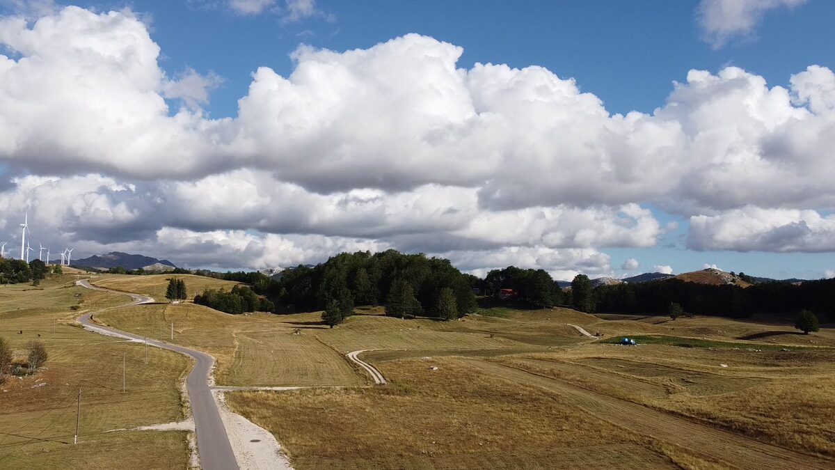 The road snaking across the plateau under summer clouds.