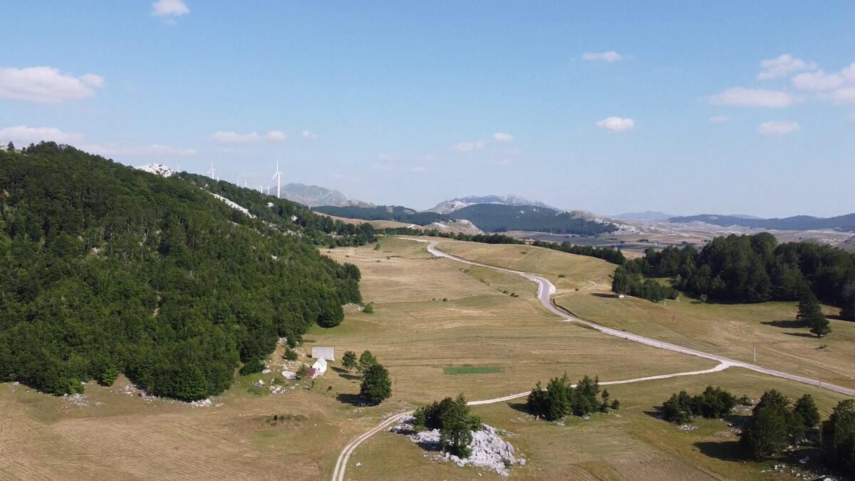 The road winding across the plateau, with the Krnovo wind farm on the ridge.